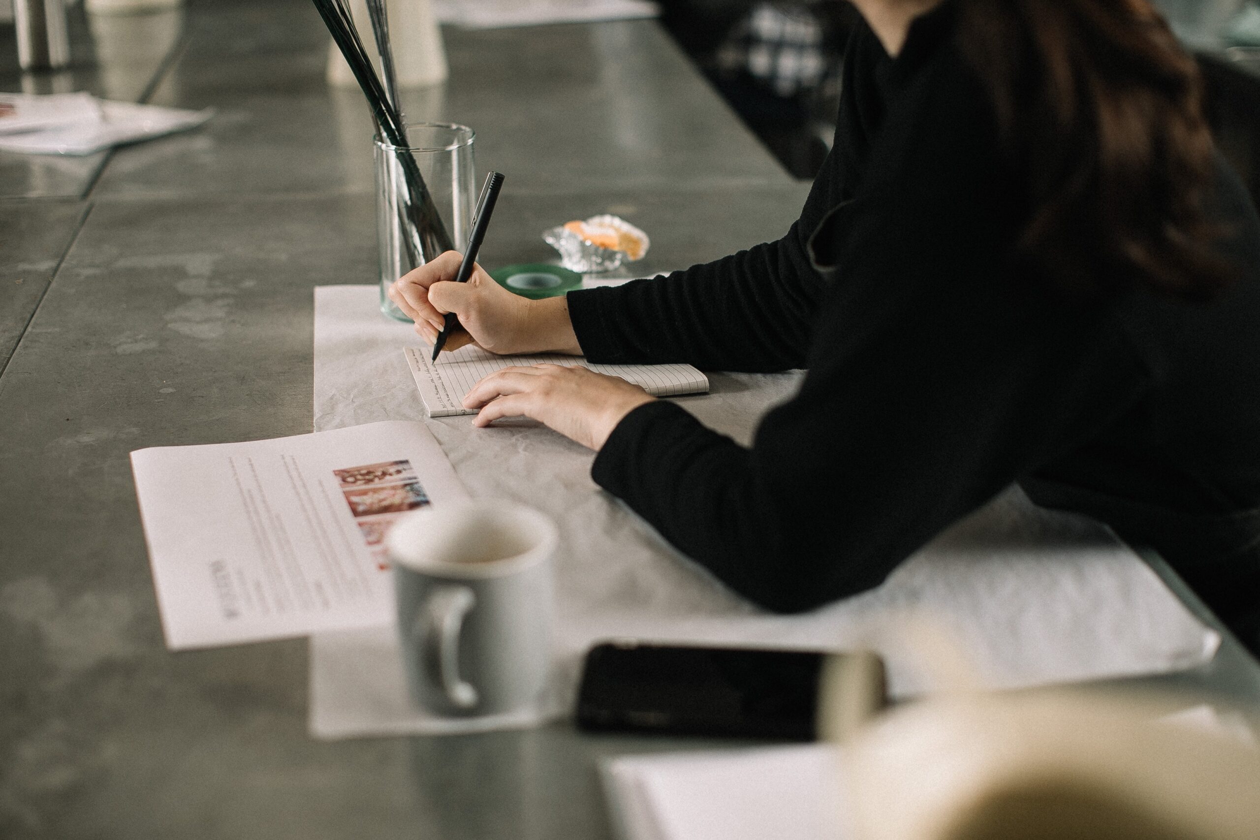 someone sitting at table writing on paper