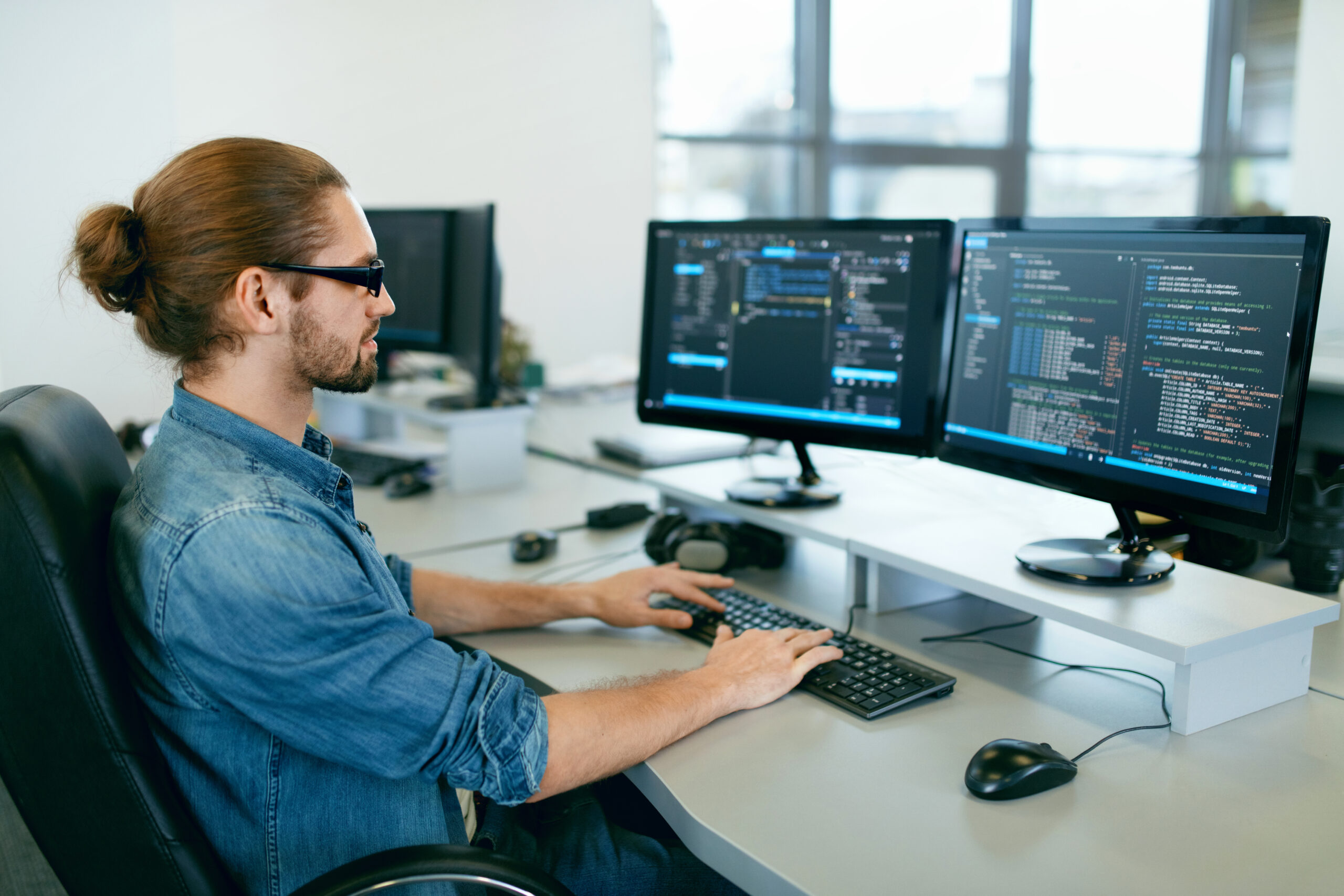 Man sitting at computer with dual screens