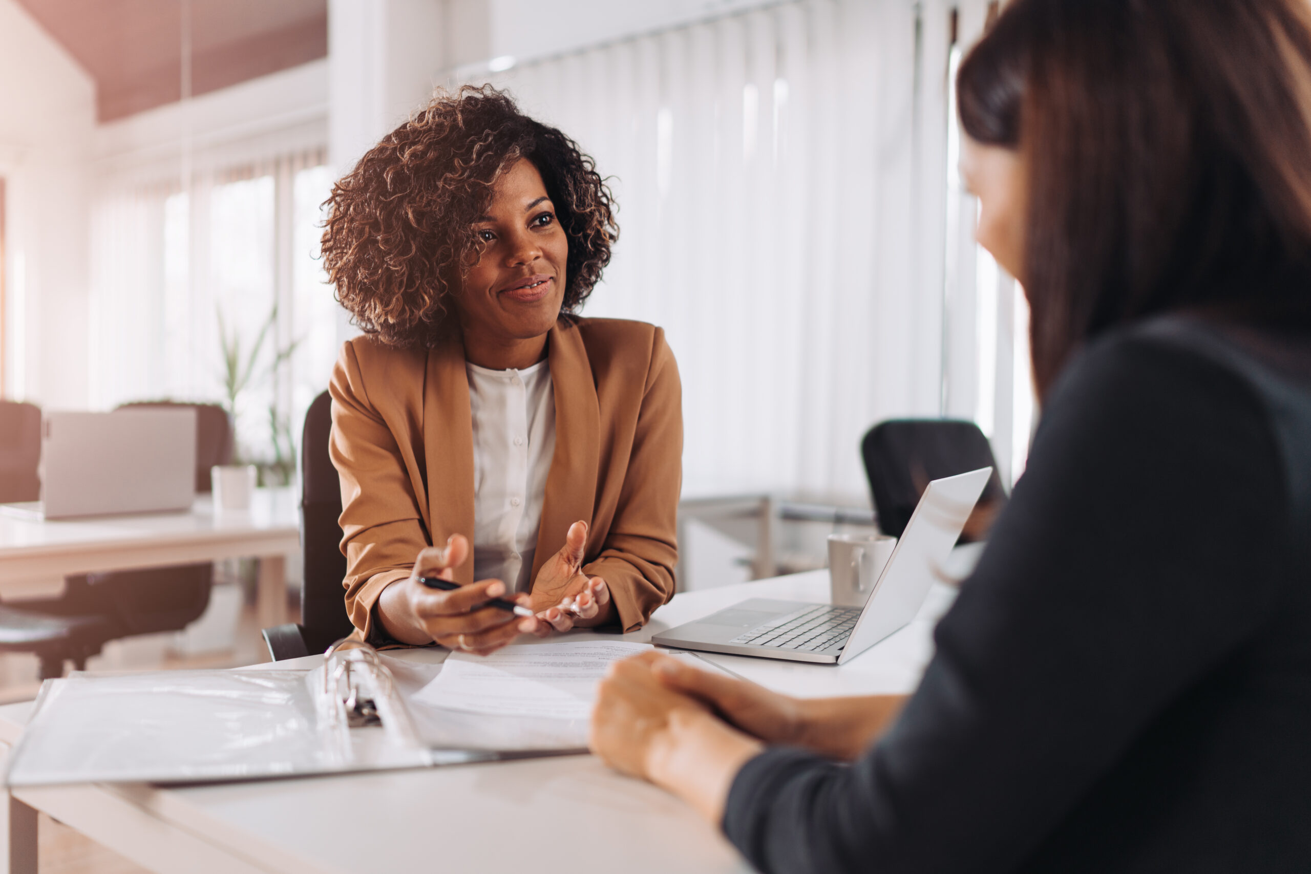 Happy women sitting at desk talking